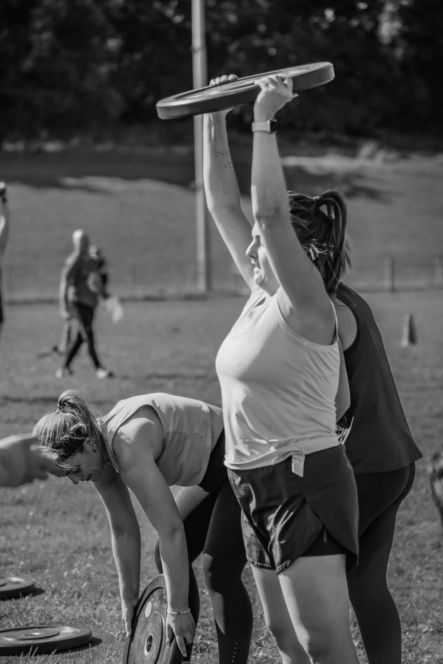 Atleta a levantar e a empurrar um disco de peso no exercício «Clean and Press»
