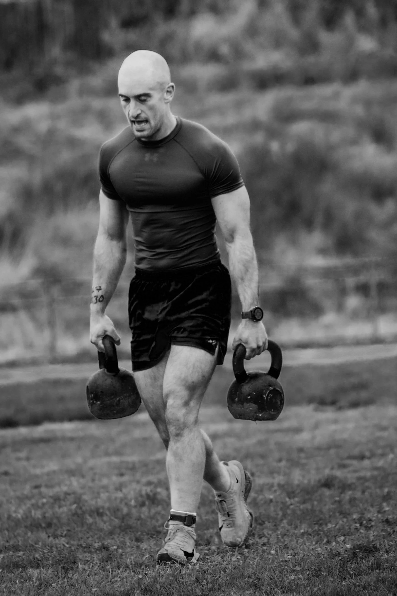 Atleta a transportar dois kettlebells ao longo da pista de 30 m na prova «Farmers Carry Labour»